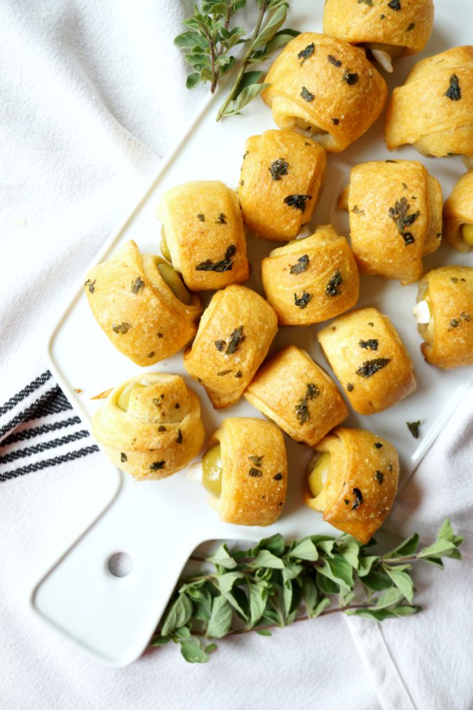 garlic stuffed olives in a blanket on cutting board.