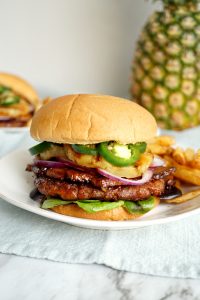 vegan aloha burger stacked with grilled pineapple, purple onion, and jalapeño slices