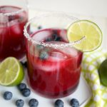 peering into a glass of blueberry margarita