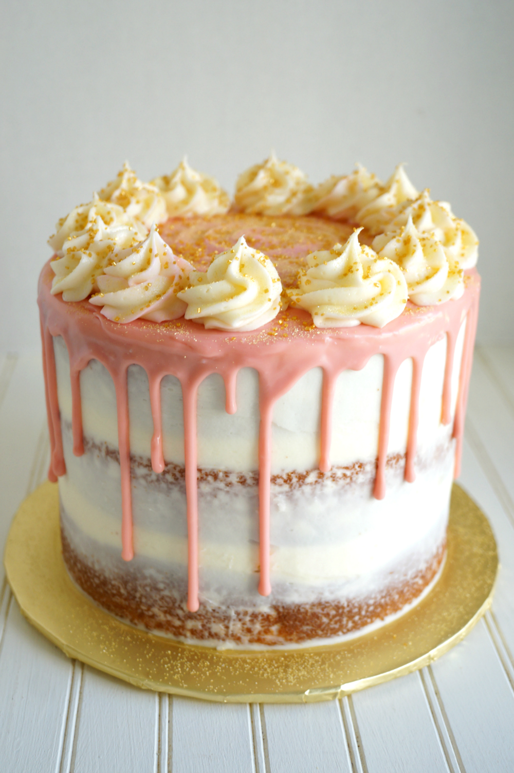 layered cake with pink drip and white frosting