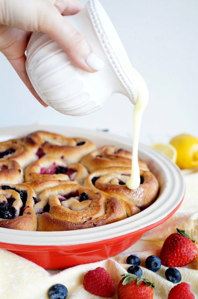 pouring glaze on lemon berry rolls