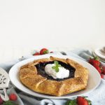 berry galette on plate with whipped cream on top