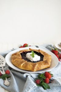 berry galette on plate with whipped cream on top