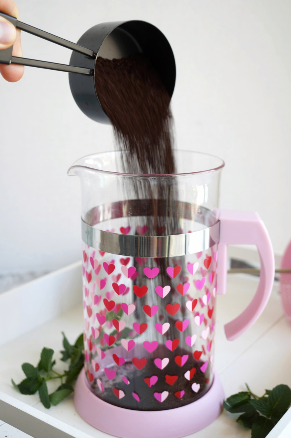 pouring ground coffee into french press