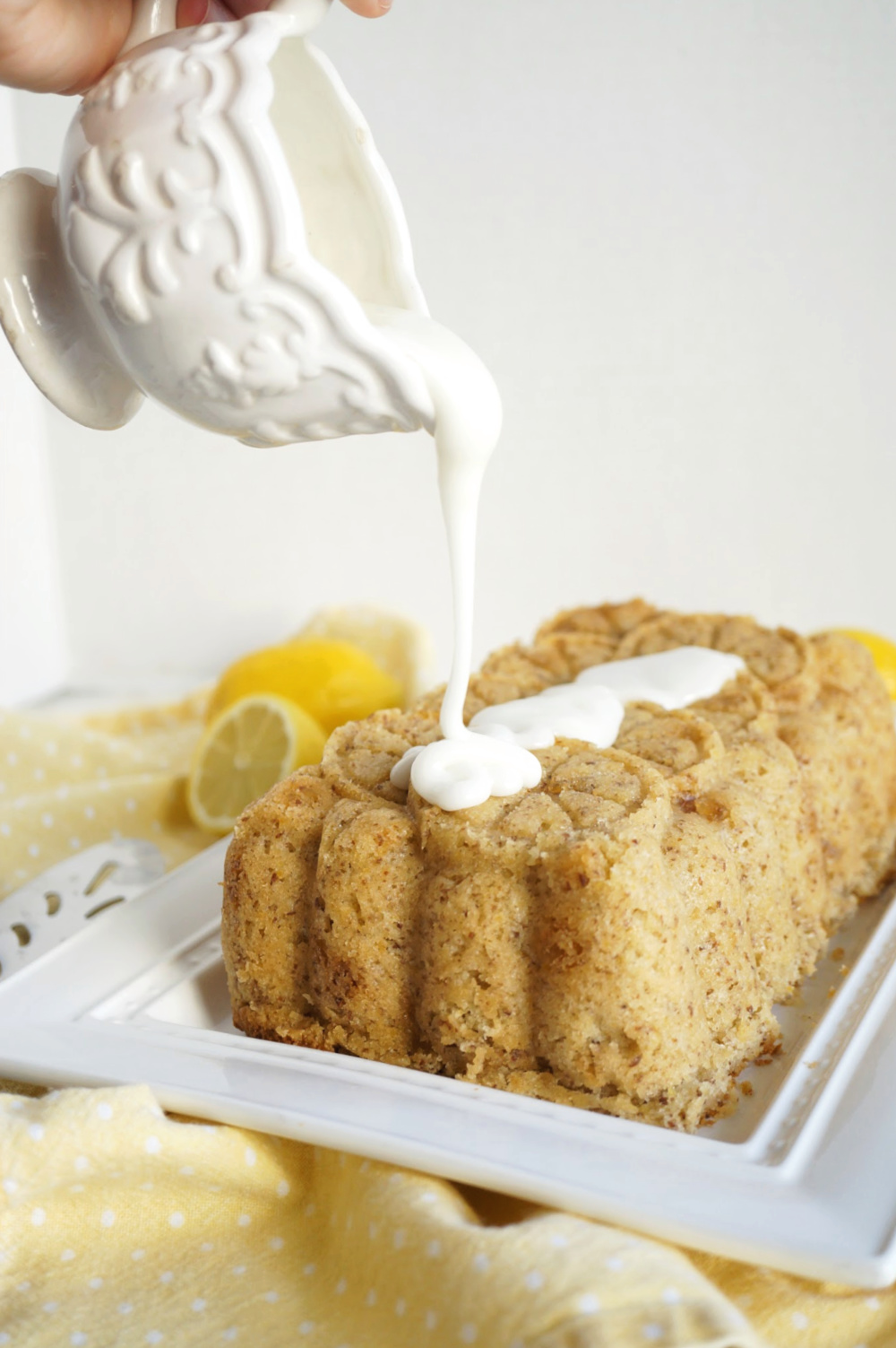 pouring lemon glaze on loaf cake