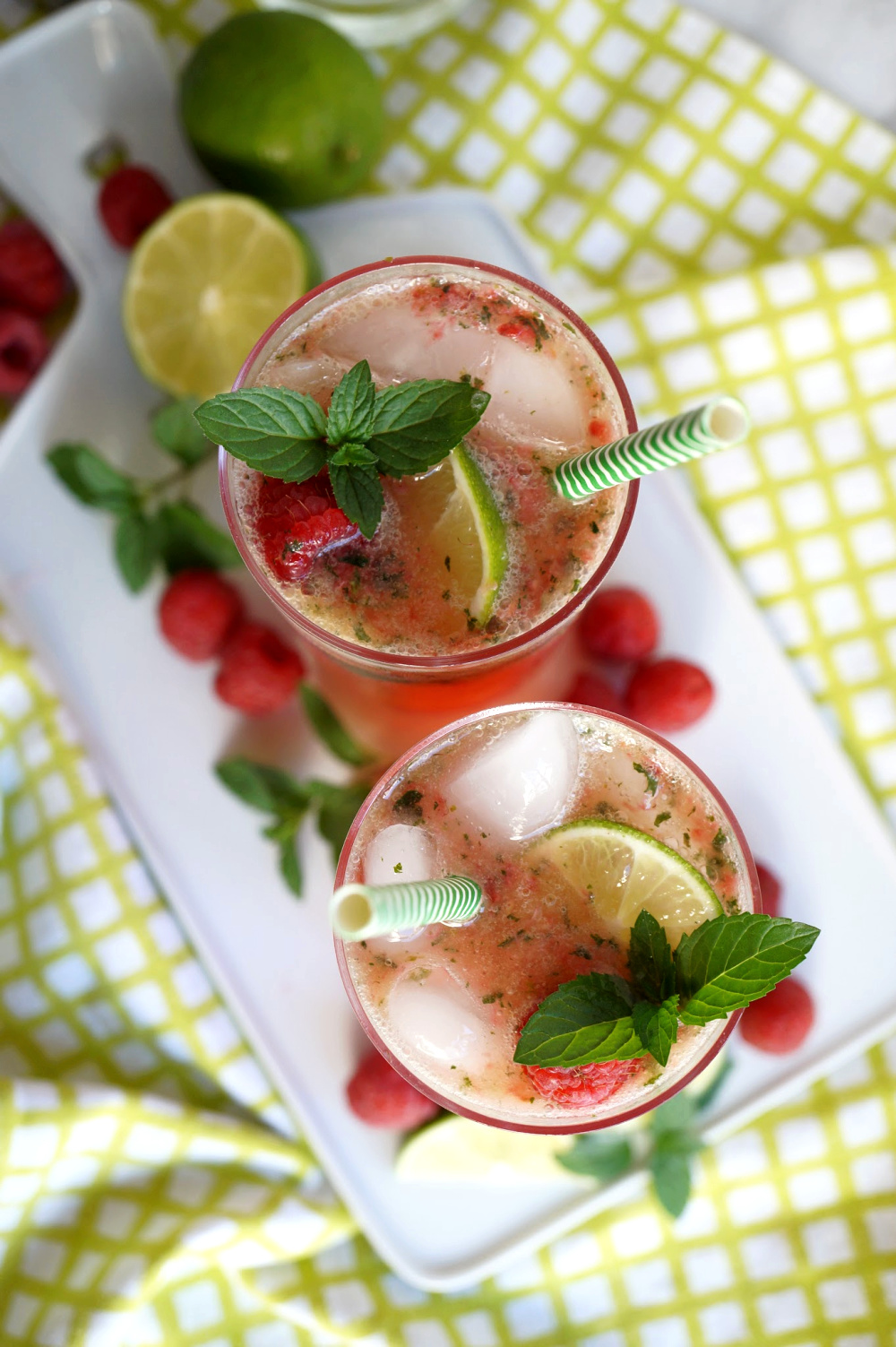 overhead shot of two glasses of raspberry coconut mojitos