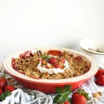 shot of pan of strawberry pistachio crisp with whipped cream on top