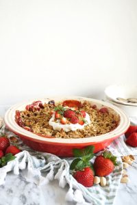 shot of pan of strawberry pistachio crisp with whipped cream on top