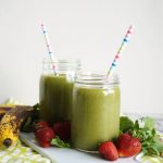 two mason jars of green smoothie with colorful straws