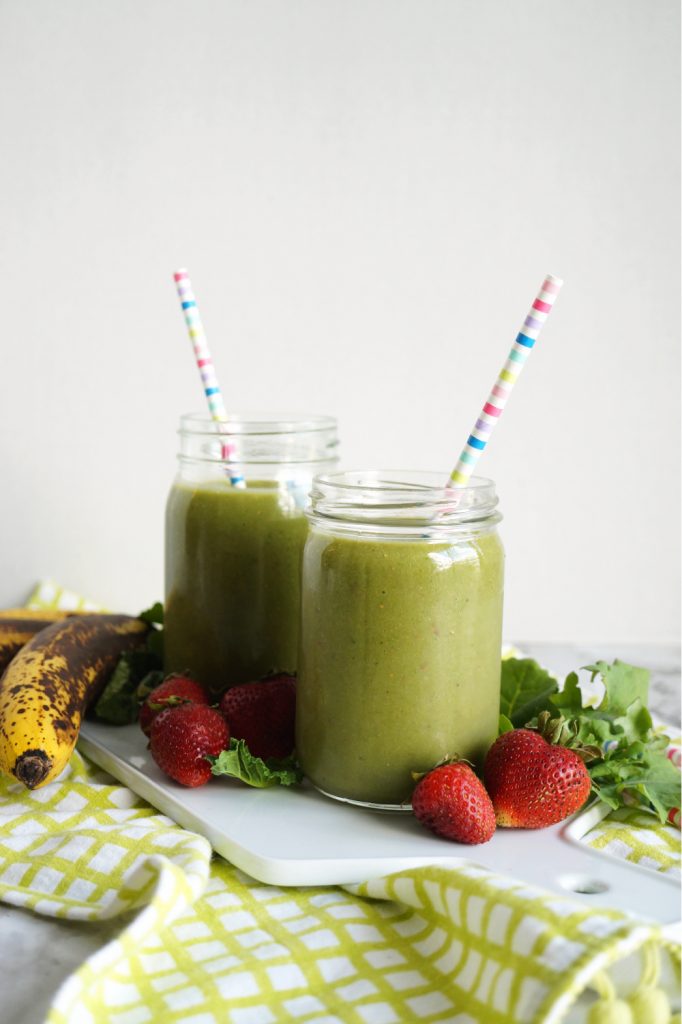 two mason jars of green smoothie with colorful straws