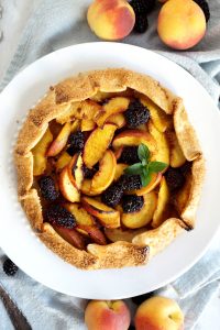 overhead photo of blackberry peach galette with sprig of mint
