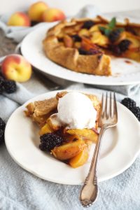 slice of blackberry peach galette on plate with ice cream