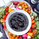 overhead shot of black lentil peppercorn hummus with colorful vegetables