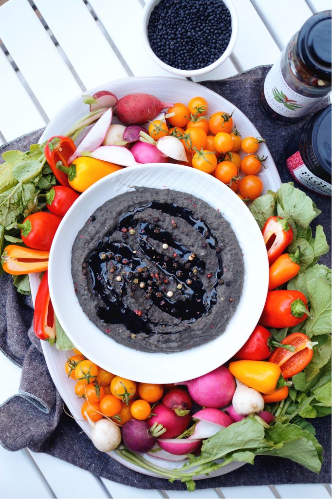 overhead shot of black lentil peppercorn hummus with colorful vegetables