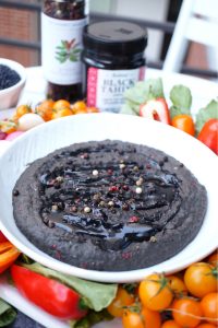 bowl of black lentil hummus with tahini drizzle and peppercorns