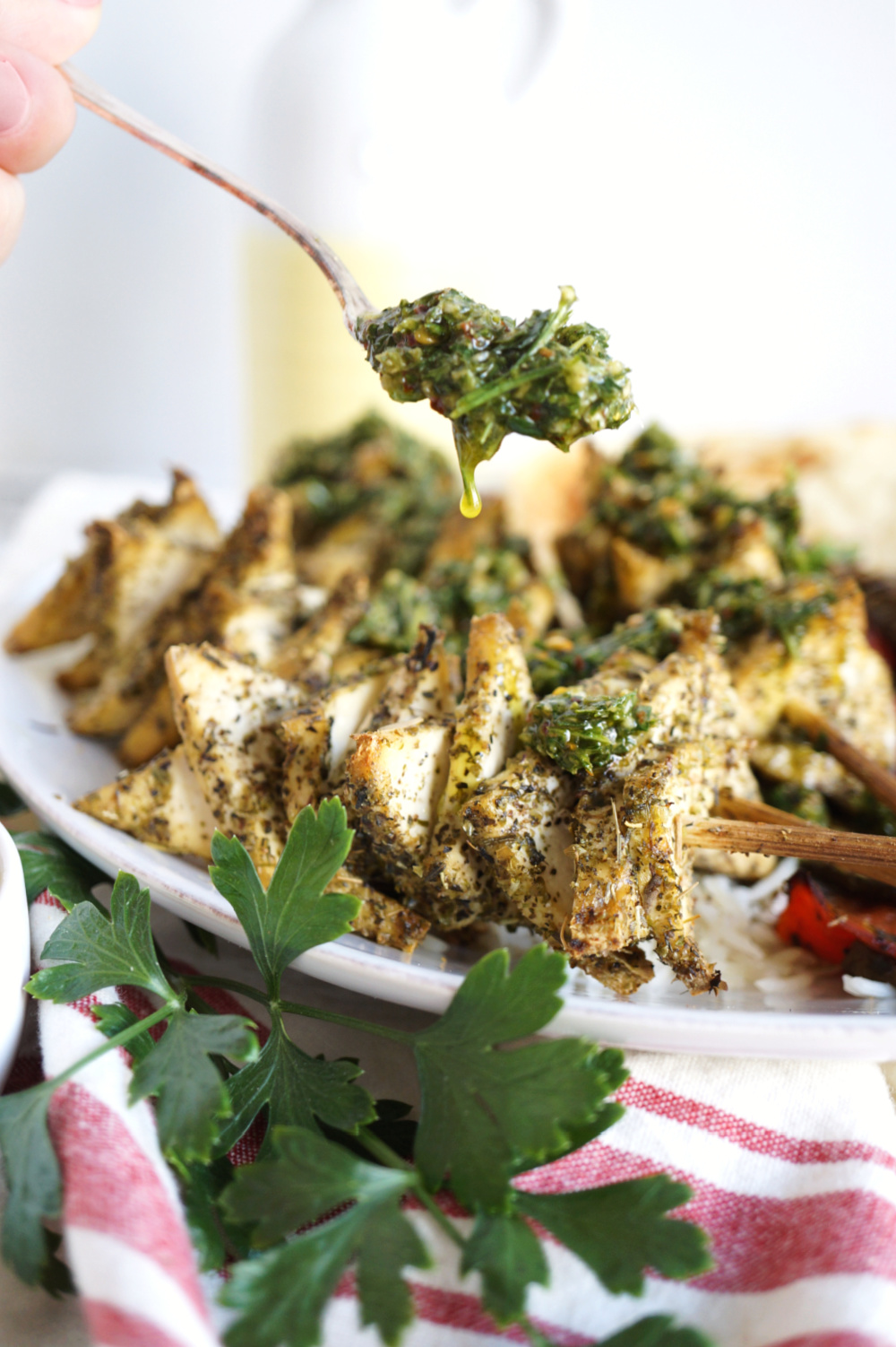 pouring chimichurri sauce on tofu skewers