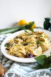 plate of spaghetti with zucchini and lemon wedge