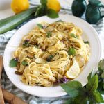 plate of pasta with zucchini, lemon slices and basil leaves