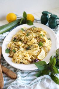 plate of pasta with zucchini, lemon slices and basil leaves