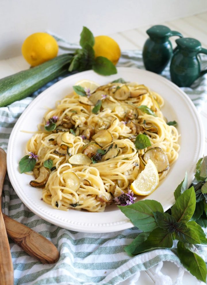 plate of pasta with zucchini, lemon slices and basil leaves