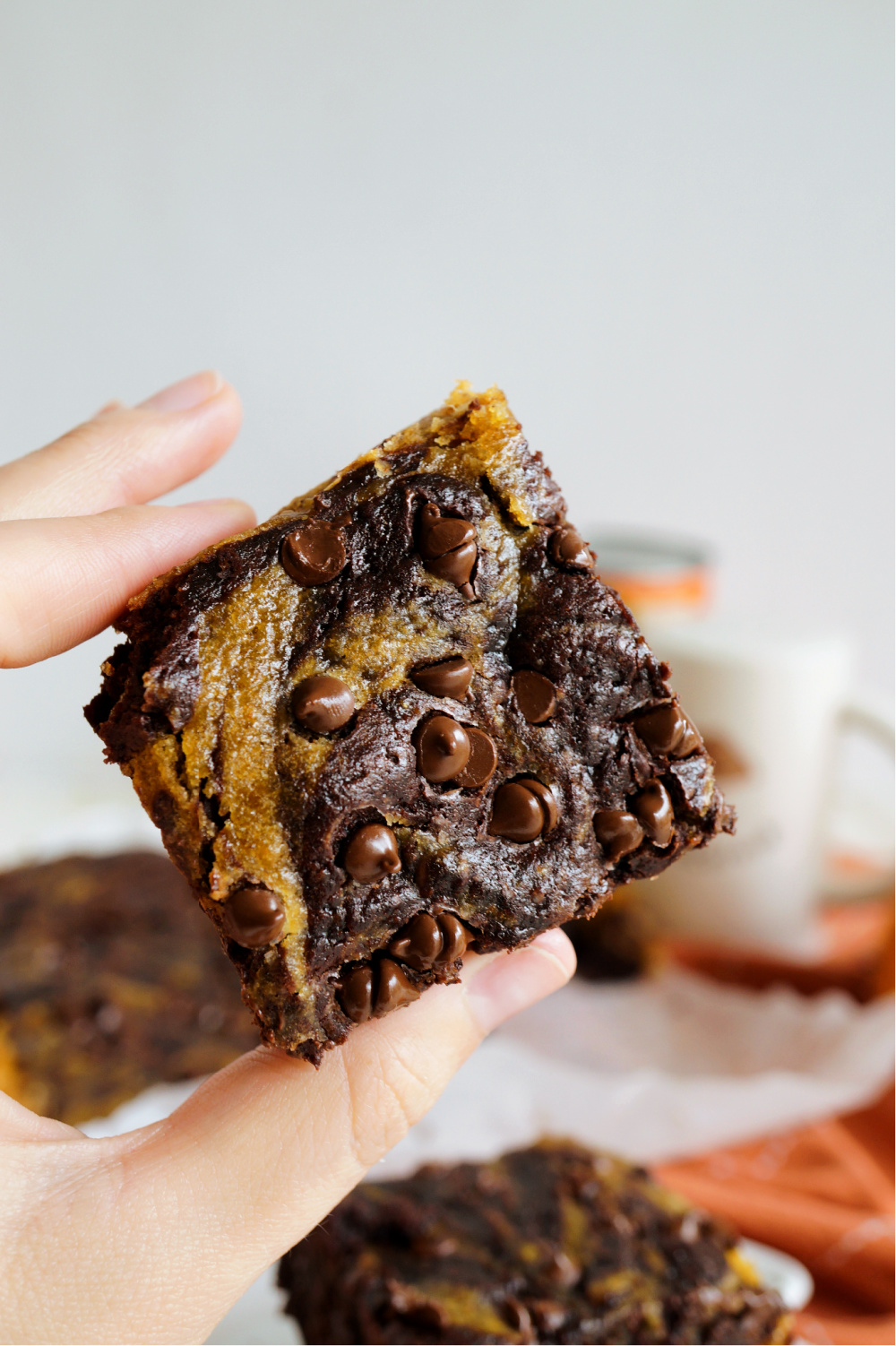 square of vegan pumpkin swirl brownie in hand