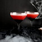 two glasses of red cocktail with spooky background and fog
