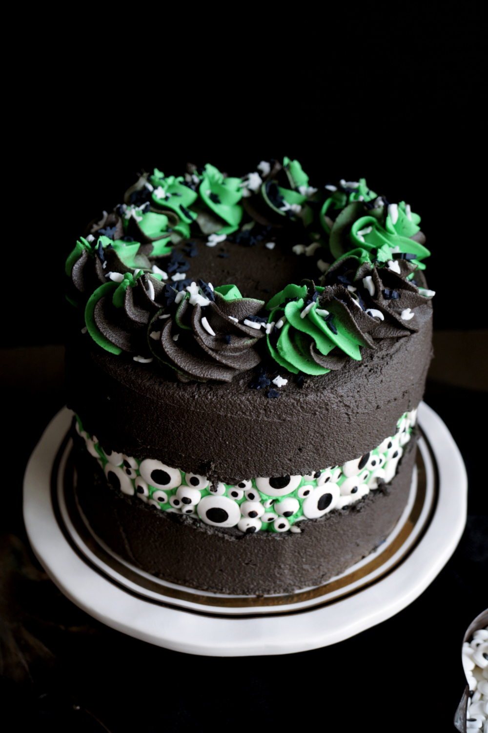 angled shot of black cake with candy eyeballs