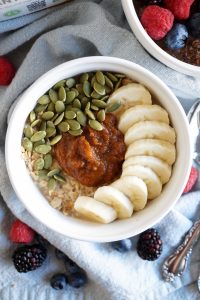 bowl of oats with pumpkin butter, pumpkin seeds, and banana