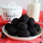 black cocoa truffles on white plate with red towel