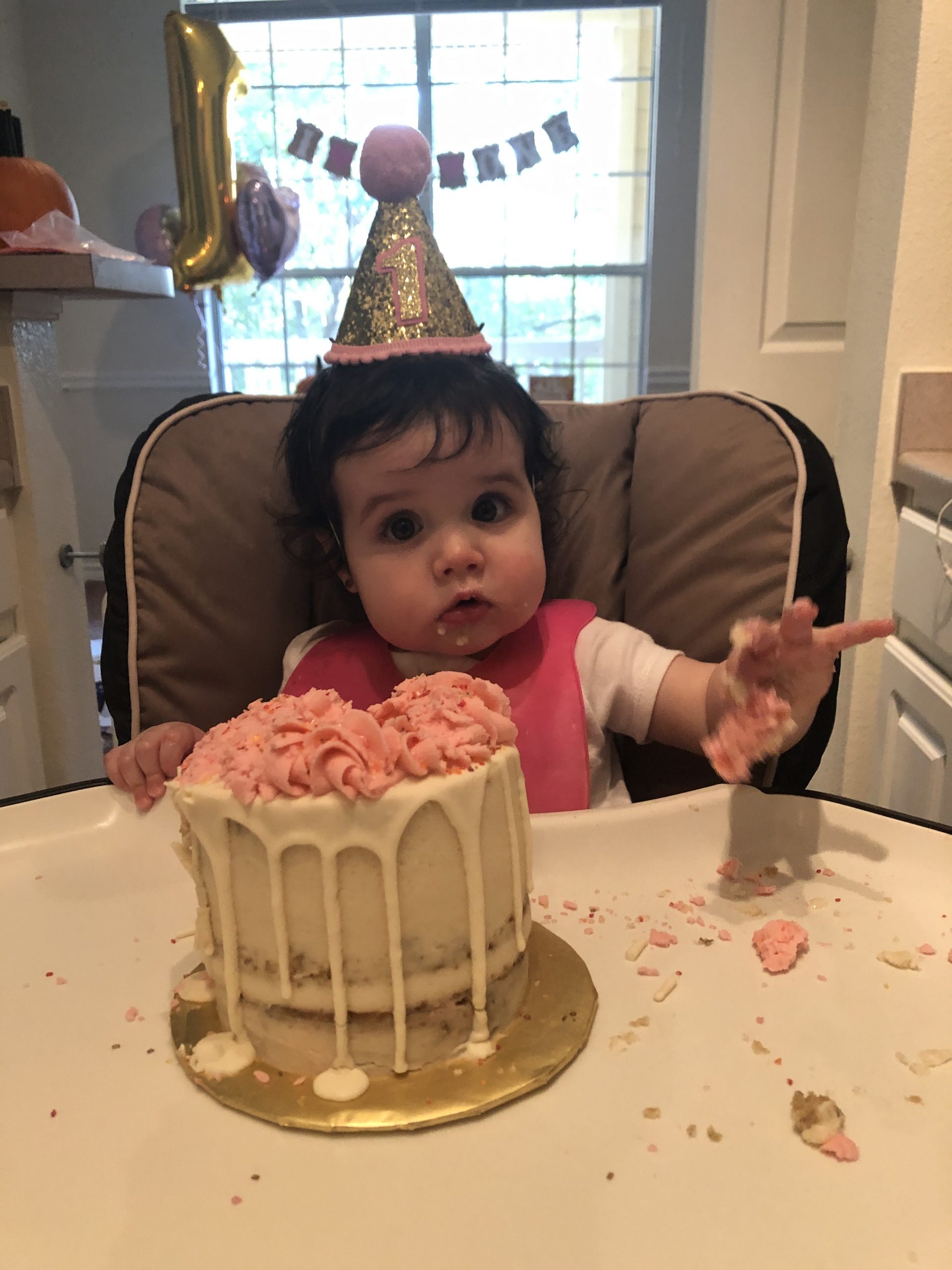 baby with a party hat and a small birthday cake