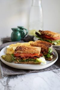 vegan BLT sandwich on a plate cut in half