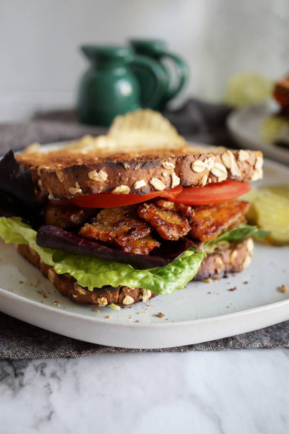 sandwich with vegan bacon, lettuce, tomato on a white plate