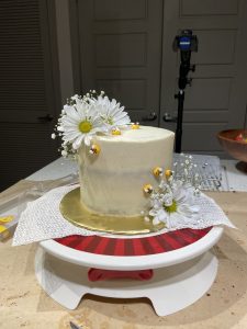 white cake with flowers and small icing bumblebees