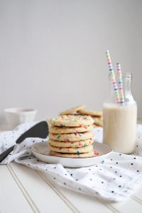 stack of confetti sugar cookies on plate with bottle of milk