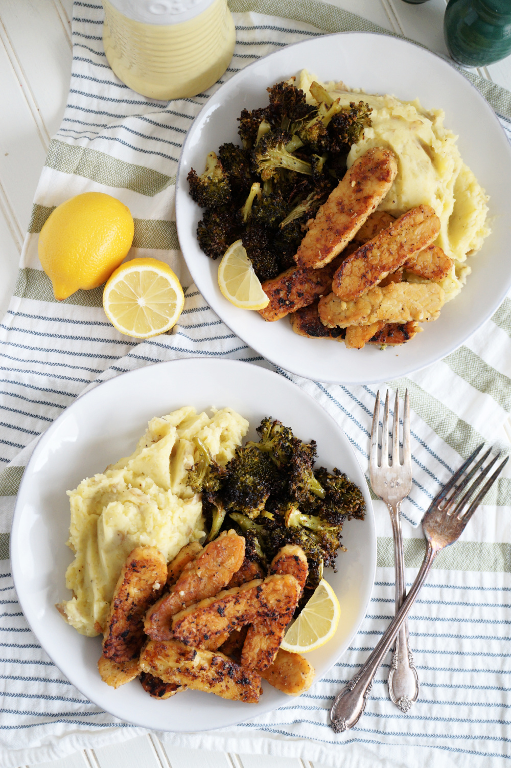 overhead shot of plates of lemon pepper tempeh with mashed potatoes and broccoli