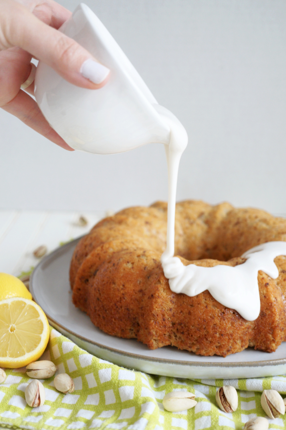 pouring white glaze on bundt cake