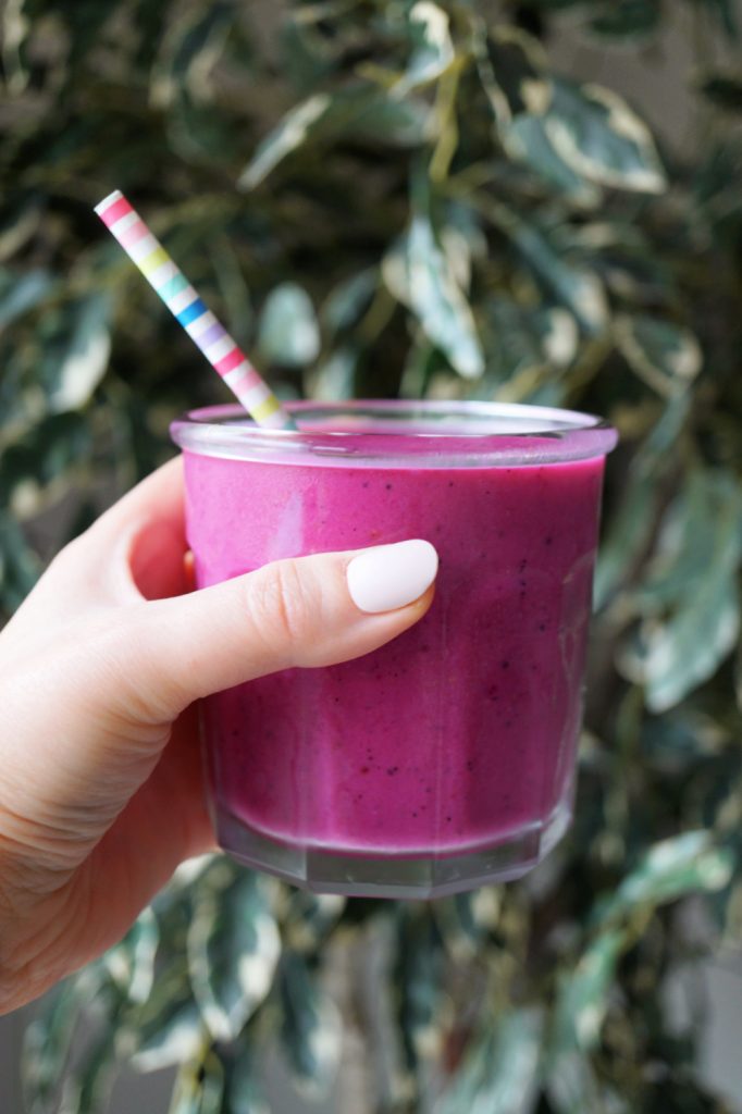 hand holding a pink pitaya protein smoothie cup