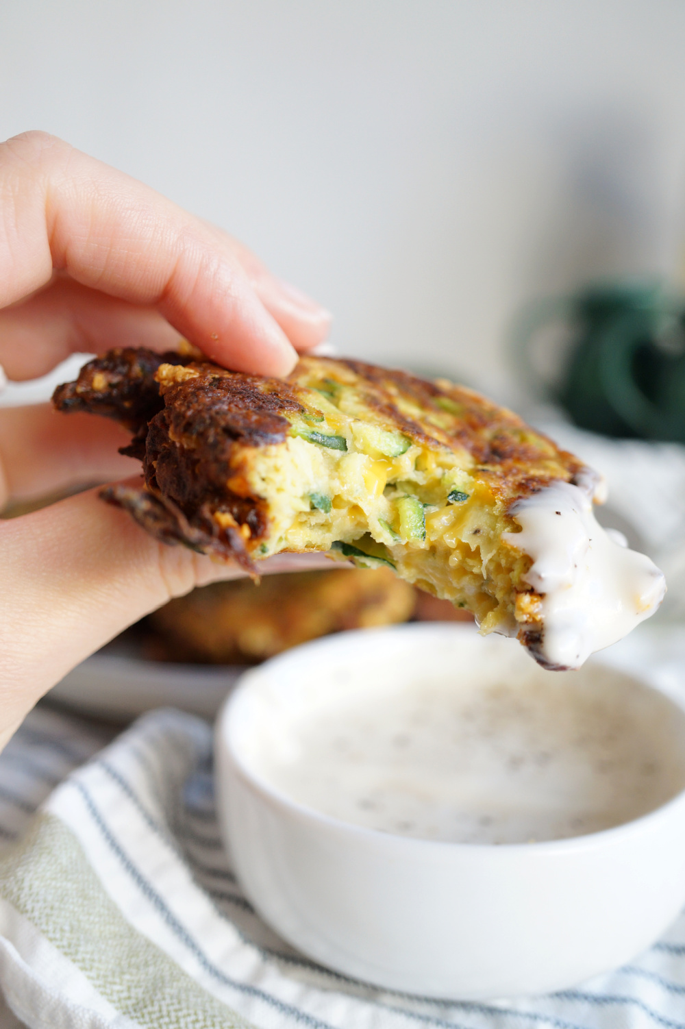 zucchini fritter in hand with a bite taken out