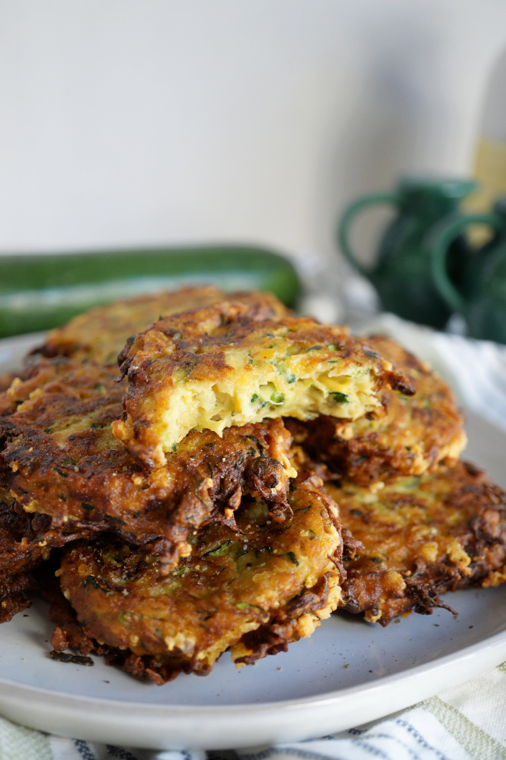 stack of zucchini fritters on plate with a bite taken out