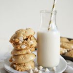 stack of white chocolate cookies next to bottle of milk