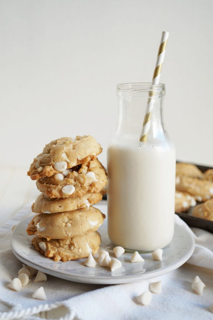 stack of white chocolate cookies next to bottle of milk