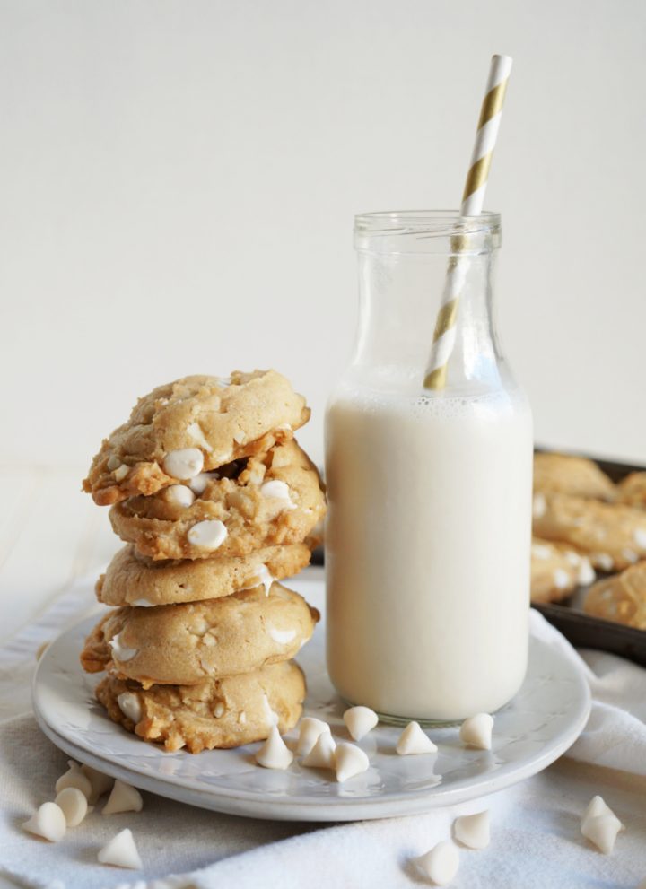 stack of white chocolate cookies next to bottle of milk