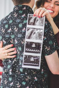 couple hugging and holding ultrasound of baby