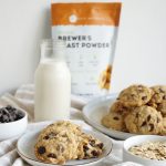 chocolate chip oatmeal cookies stacked on small white plate with bottle of milk in background