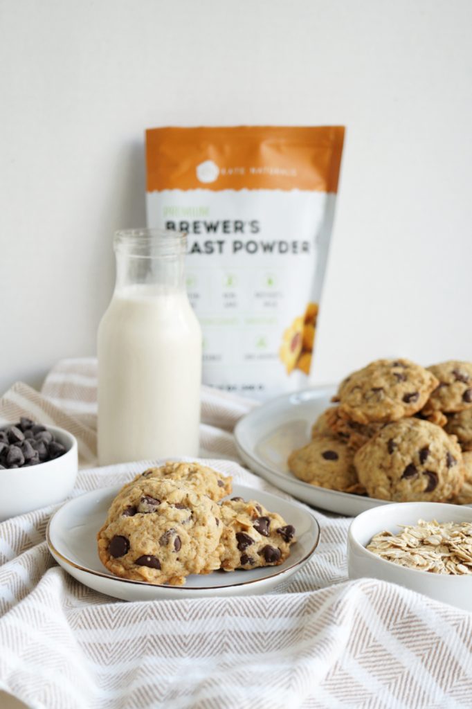 chocolate chip oatmeal cookies stacked on small white plate with bottle of milk in background