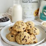 stack of oatmeal chocolate chip cookies on large plate with bag of brewer's yeast in background