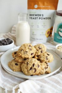 stack of oatmeal chocolate chip cookies on large plate with bag of brewer's yeast in background